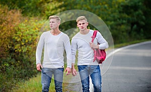 Means of travel. twins walking along road. two brothers go adventure. friendship. men hitch hiking. man casual style