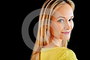 Meant to stand out. Studio portrait of a beautiful young blonde woman looking over her shoulder isolated on black.