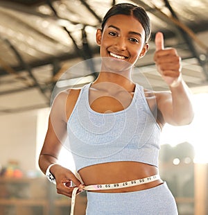 Measure, lose weight or happy woman with thumb up or tape for waist or body goals in fitness studio. Gym, thumbs up or