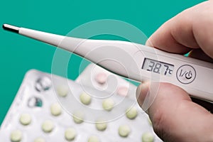 Measurement of body temperature with  digital thermometer. Tablets that help relieve the patient`s condition.