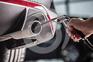 Measurement of exhaust emissions at the technical inspection station. A car repairman applies a probe to the exhaust