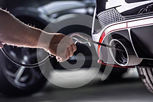 Measurement of exhaust emissions at the technical inspection station. A car repairman applies a probe to the exhaust