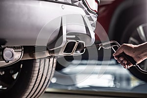 Measurement of exhaust emissions at the technical inspection station. A car repairman applies a probe to the exhaust