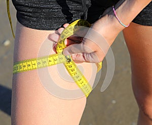 measurement of the thigh circumference of the leg of girl with  tape measure and measures in centimeters