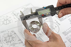 Measurement of a turned part. Electronic caliper in the technician`s hand. A round steel piece in the jaw of a measuring tool wit