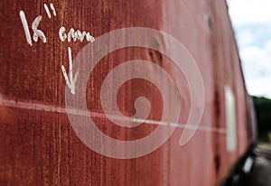 Measurement values shown in a shallow focus, written by hand on the side of an old, weathered railway carriage.