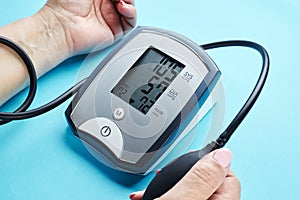 measuring blood pressure with electronic medical device over blue background
