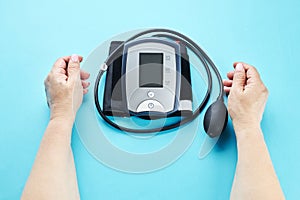 measuring blood pressure with electronic medical device over blue background