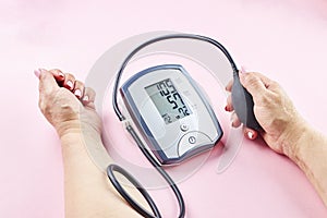 measuring blood pressure with electronic medical device over pink background