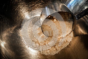 Measuring a cup of almond flour into a stainless steel bowl with a measuring cup - Close up and selective focus