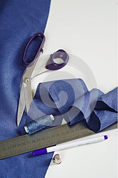 Measuring and cutting textile. Scissors and violet linen fabric.