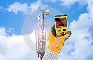Measuring electromagnetic radiation from a cell tower. The device indicates hazardous radiation with text Danger.