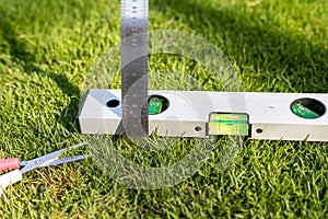 measuring grass with a ruler and levelling with a spirit level tool after cutting the grass. Compulsive obsessive disorder