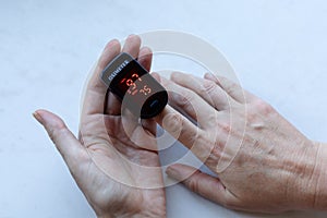 Measuring of Oxygen level in blood with home oximeter, Oximeter in woman`s hands photo