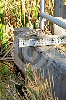 Measuring ruler to determine how much water or rain there is in the local pond or lake in industrial area