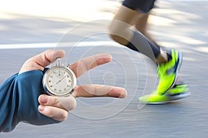 Measuring the running speed of an athlete using a mechanical stopwatch. hand with a stopwatch on the background of the legs of a