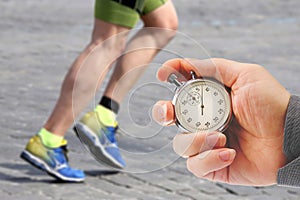 Measuring the running speed of an athlete using a mechanical stopwatch. hand with a stopwatch on the background of the legs of a