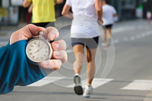 Measuring the running speed of an athlete using a mechanical stopwatch. hand with a stopwatch on the background of the legs of a