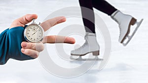 A measuring speed on skates with a stopwatch. hand with a stopwatch on the background of the legs of a man skating on an ice rink