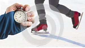 Measuring speed on skates with a stopwatch. hand with a stopwatch on the background of the legs of a man skating on an ice rink