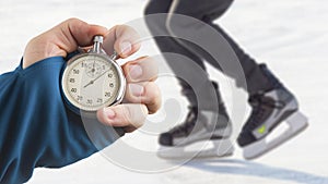 Measuring speed on skates with a stopwatch. hand with a stopwatch on the background of the legs of a man skating on an ice rink