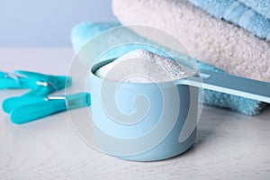 Measuring spoon of laundry powder near towels and clothespins