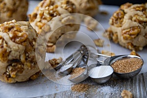 Measuring spoons in front of walnut cookie dough balls with crumbles arount it
