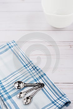 Measuring spoons sit on top of a plaid dishtowel