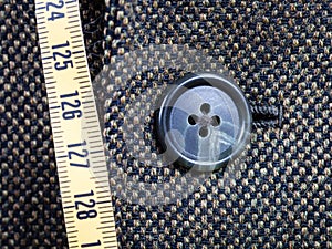 Measuring tape and buttoned button on tweed jacket