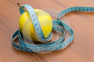 Measuring tape and green apple on wooden table. Concept of diet and healthy lifestyle