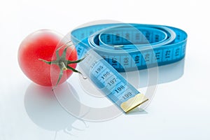 Measuring tape and juicy tomato, the concept of healthy nutrition and weight loss