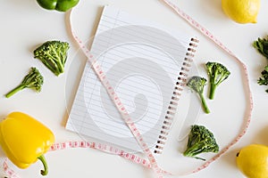 Measuring tape, note pad with clean pages and fresh vegetables and fruits on white background