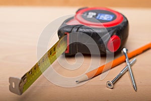 Measuring tape, pencil, screws on wooden table