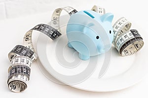 a measuring tape and a piggy bank in a white plate