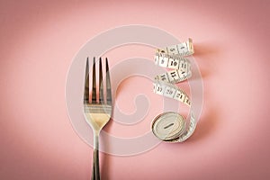 Measuring tape and plug on pink background. The concept of dieting