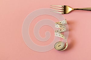 Measuring tape and plug on pink background. The concept of dieting