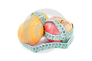 Measuring tape twisted around apples and oranges