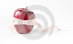 Measuring tape wrapped around apple, as a symbol of diet.