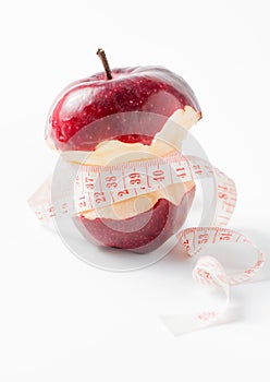 Measuring tape wrapped around apple as a symbol of diet.