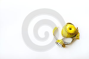 Measuring tape wrapped around fresh tasty yellow apple isolated on white background. Diet, weight loss, fitness, sport