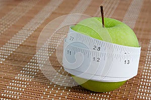 Measuring tape wrapped around a green apple