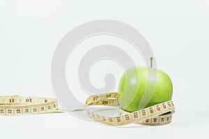 Measuring tape wrapped around a green apple.