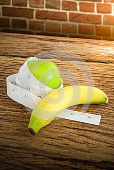 Measuring tape wrapped around a green apple and banana