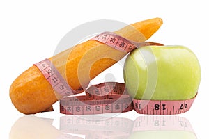 Measuring tape wrapped around a green apple and carrot