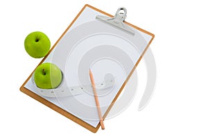 Measuring tape wrapped around a green apple and clipboard