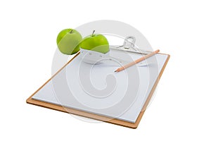 Measuring tape wrapped around a green apple and clipboard