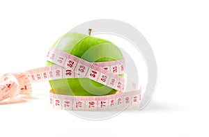 Measuring tape wrapped around a green apple isolated on white