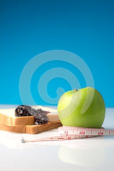 Measuring tape wrapped around a green apple with Slice of white