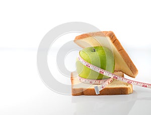 Measuring tape wrapped around a green apple with Slice of white