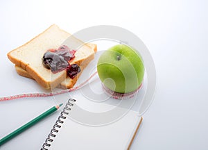 Measuring tape wrapped around a green apple with Slice of white